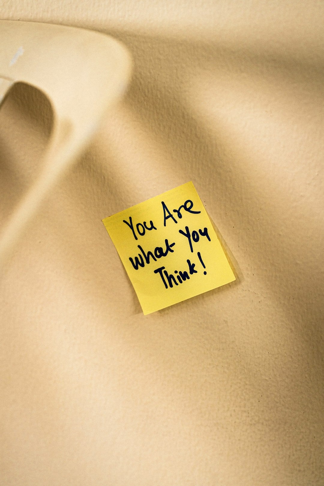 Yellow sticky note with handwritten motivational text on a surface.